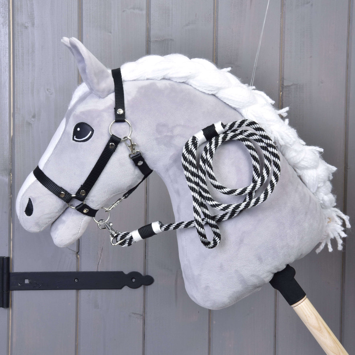 Hobby Horse gris avec licol noir et longe rayée noire accrochée, pendant en boucles le long de l’encolure