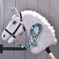 Grijze Hobby Horse met witte gevlochten manen en zwart halster, het groen gestreepte halstertouw onder de kin vastgeklikt