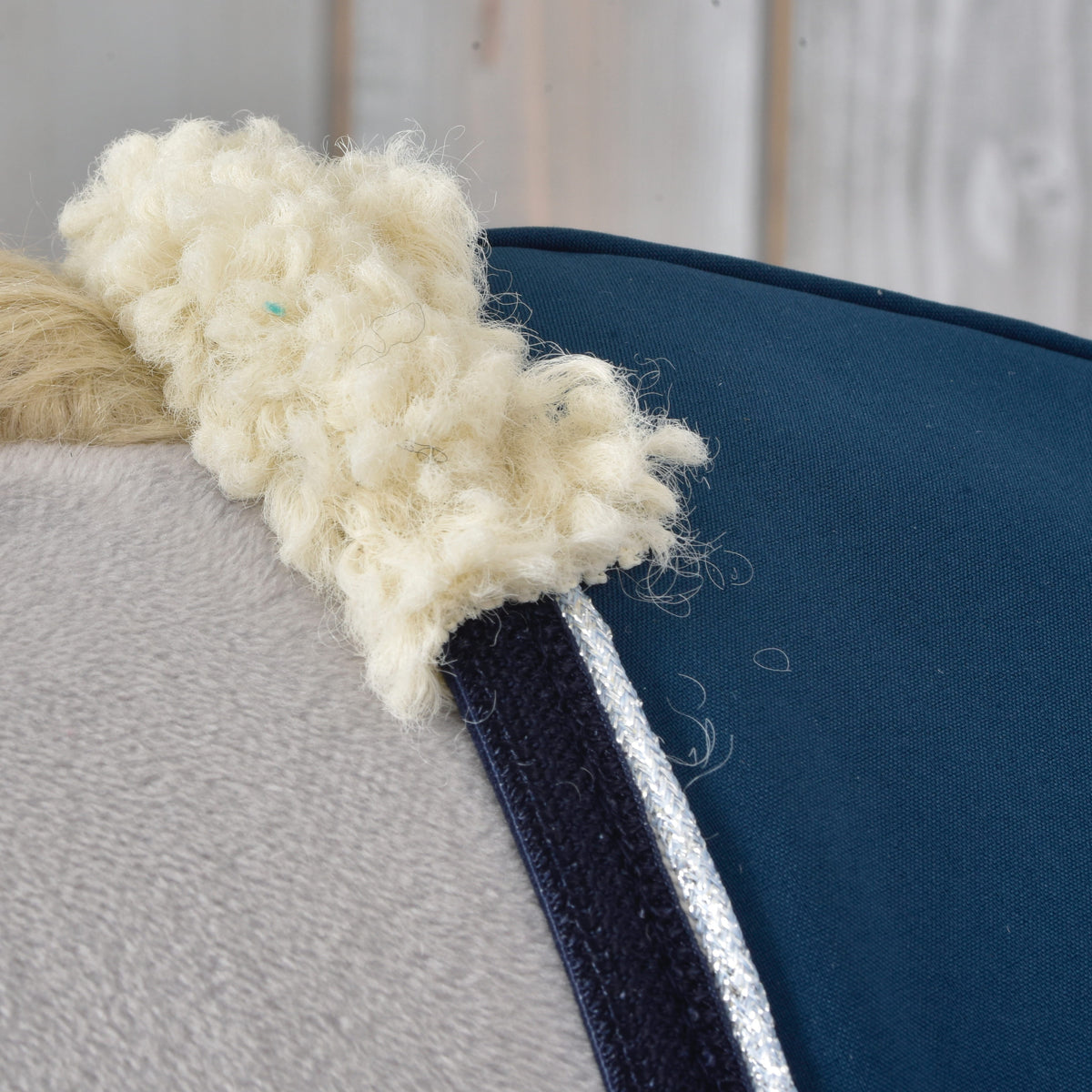 Gros plan sur le col en polaire bouclée crème, la bordure marine et le passepoil argent pailleté de la couverture d'écurie Winter Sky sur un Hobby Horse