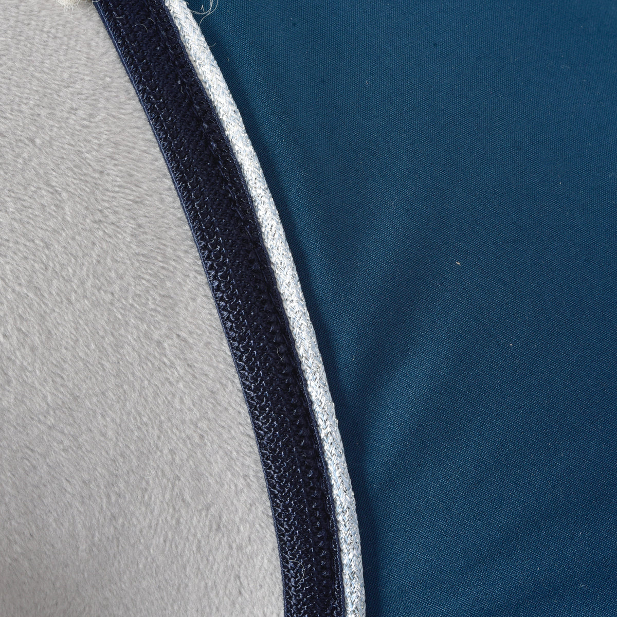 Macro de la bordure marine et du passepoil argent pailleté le long du tissu bleu pétrole de la couverture d'écurie Winter Sky pour Hobby Horse