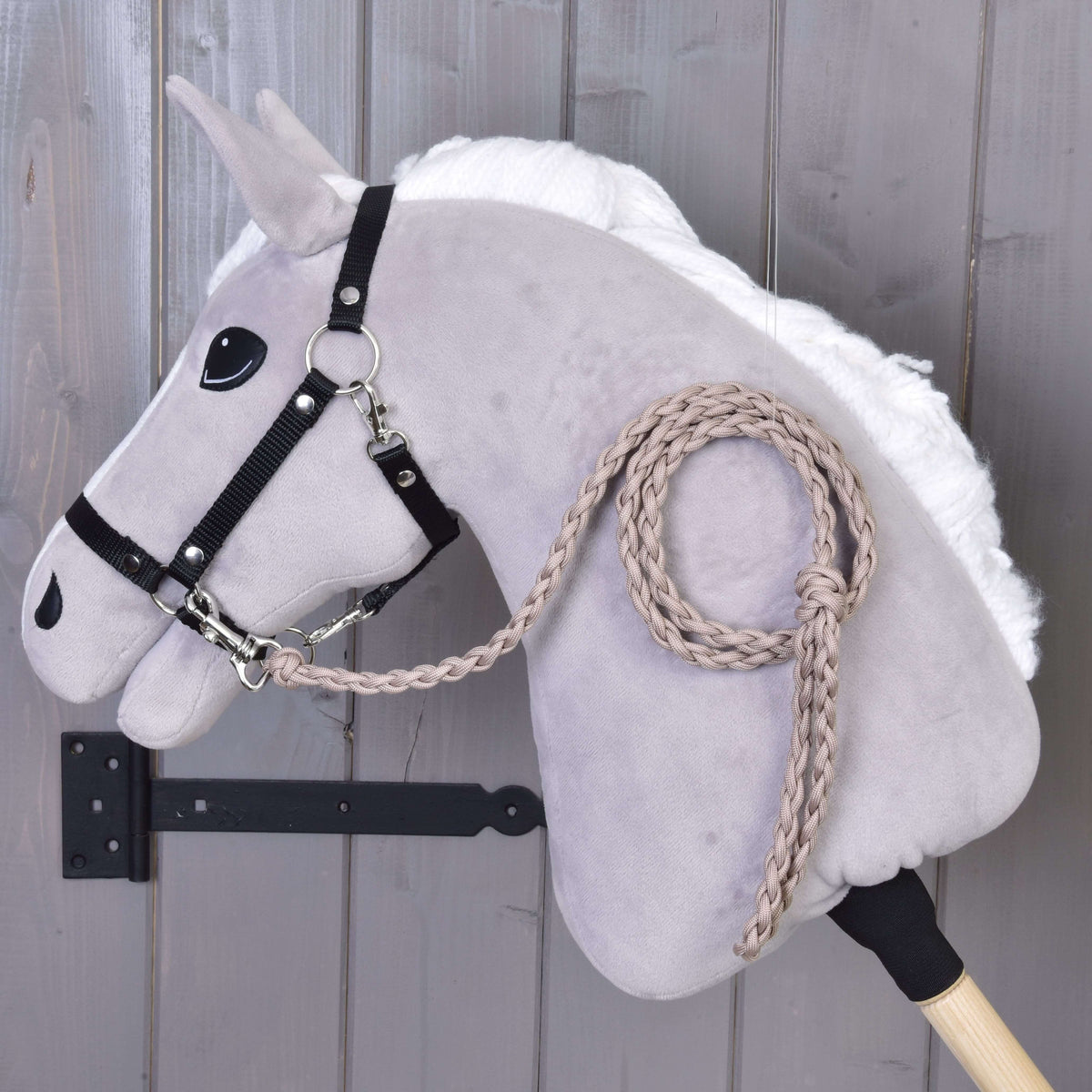Longe tressée taupe accrochée au licol noir d’un Hobby Horse gris clair à crinière blanche