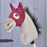 Paardenmasker Barn Red van LarDen op een beige Hobby Horse, donkerrode stretchstof met puntige oorkapjes en oogopeningen