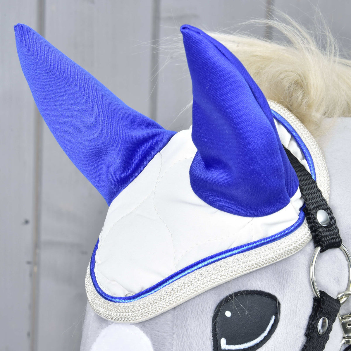Gros plan du bonnet d’oreilles Cream Pearl sur un Hobby Horse gris : oreilles bleu roi, matelassage crème et bord argent pailleté