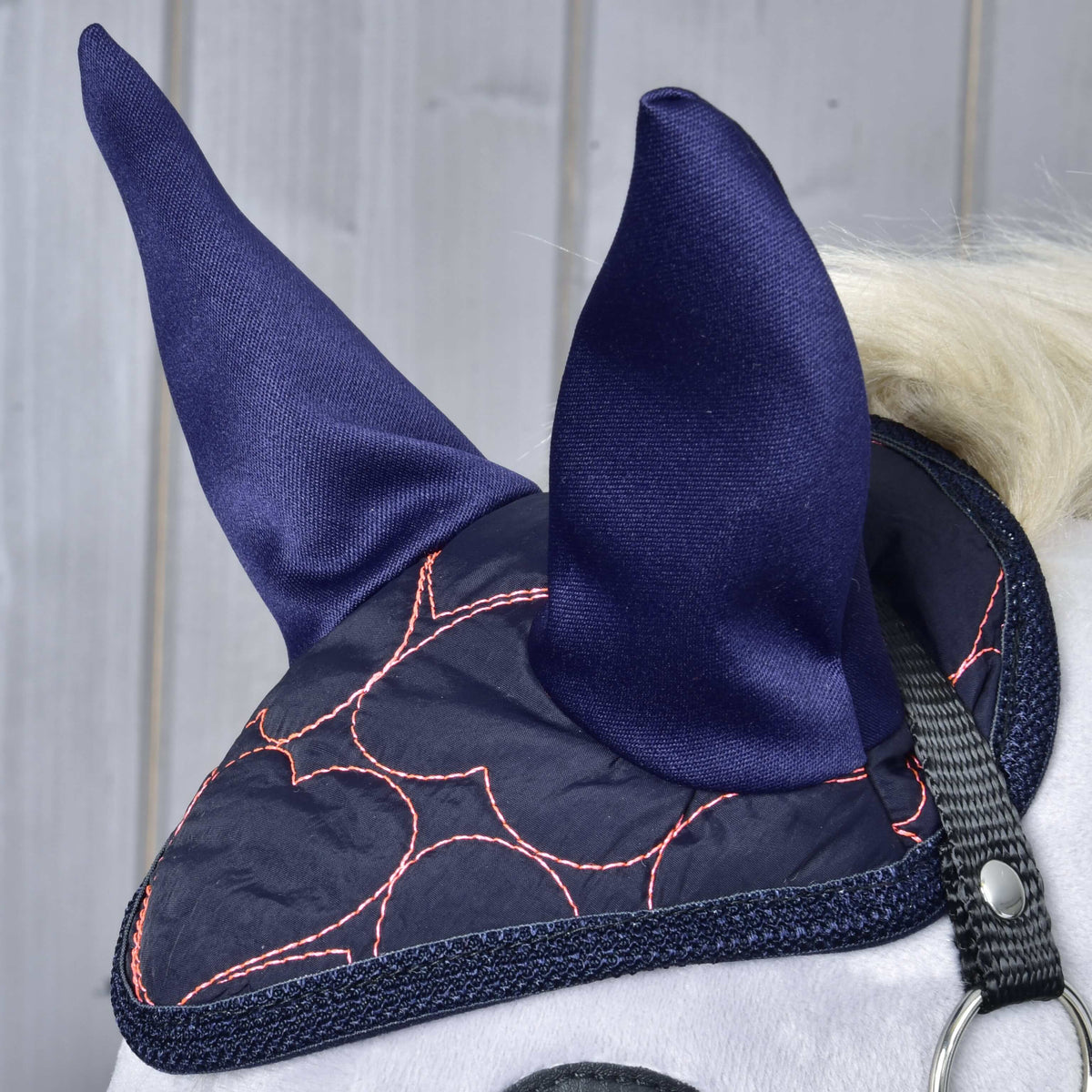 Gros plan du bonnet d’oreilles Pink Heart sur un Hobby Horse gris : oreilles bleu marine et matelassage cœurs roses au-dessus du licol noir