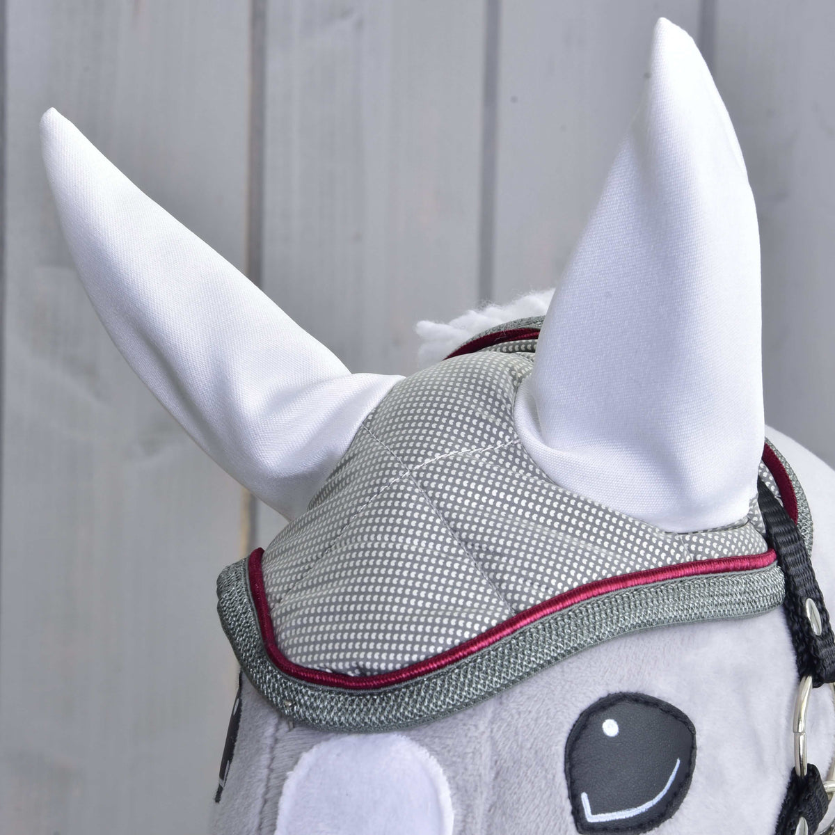 Front close-up of the dotted silver grey ear bonnet with white ears and raspberry trim on a grey Hobby Horse