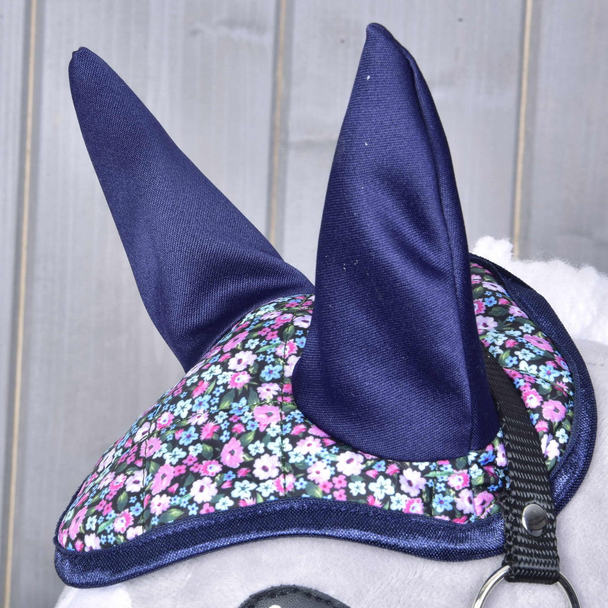 Close-up of the navy ears and quilted flower print crown with navy binding on the head of a grey Hobby Horse