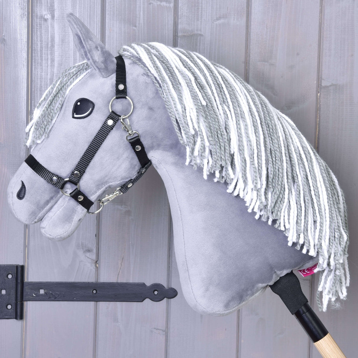 Hobby Horse Calypso in left profile, the grey and white yarn mane falling over the neck, with a black halter