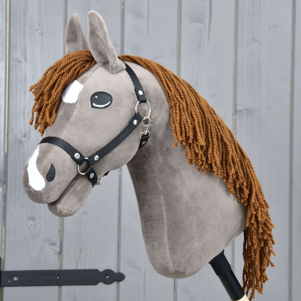 Hobby Horse Chanell avec licol noir de LarDen, tête en peluche gris-brun, crinière rousse en fil et marques blanches sur la tête