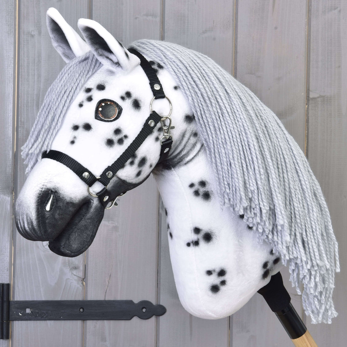 Hobby Horse Chantal avec licol noir de LarDen, tête en peluche blanche à taches noires et longue crinière grise en fil