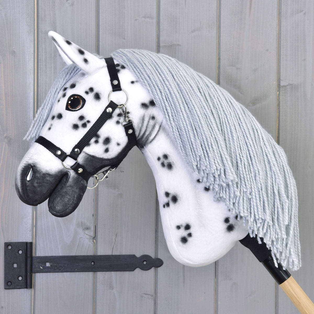 Hobby Horse Chantal avec sa longue crinière grise en fil sur l’encolure tachetée et licol noir à anneaux argentés