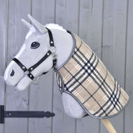 Lichtgrijze Hobby Horse met zwart halster draagt de beige geruite deken met zwarte en witte strepen