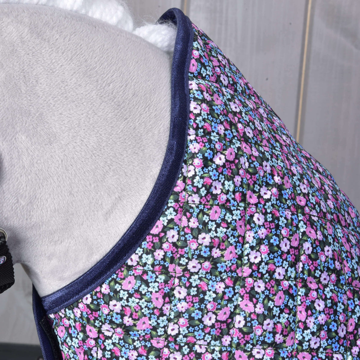 Gros plan sur l’encolure de la couverture fleurie sur un Hobby Horse gris, tissu matelassé bordé de satin bleu marine