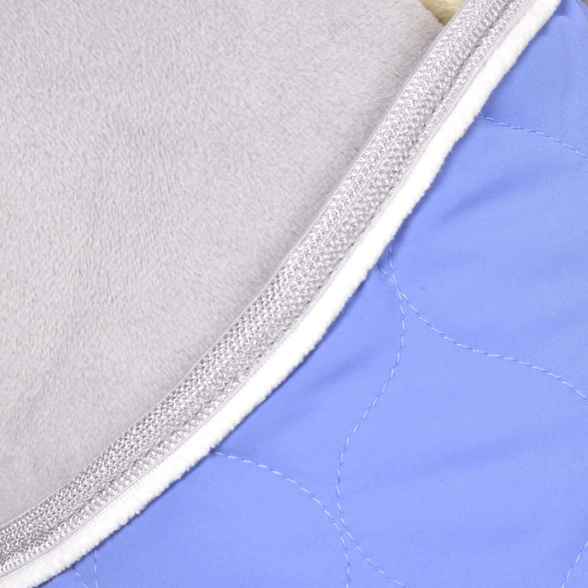 Gros plan de l’encolure de la couverture Light Violett : galon tressé gris argent et passepoil blanc sur matelassage violet clair
