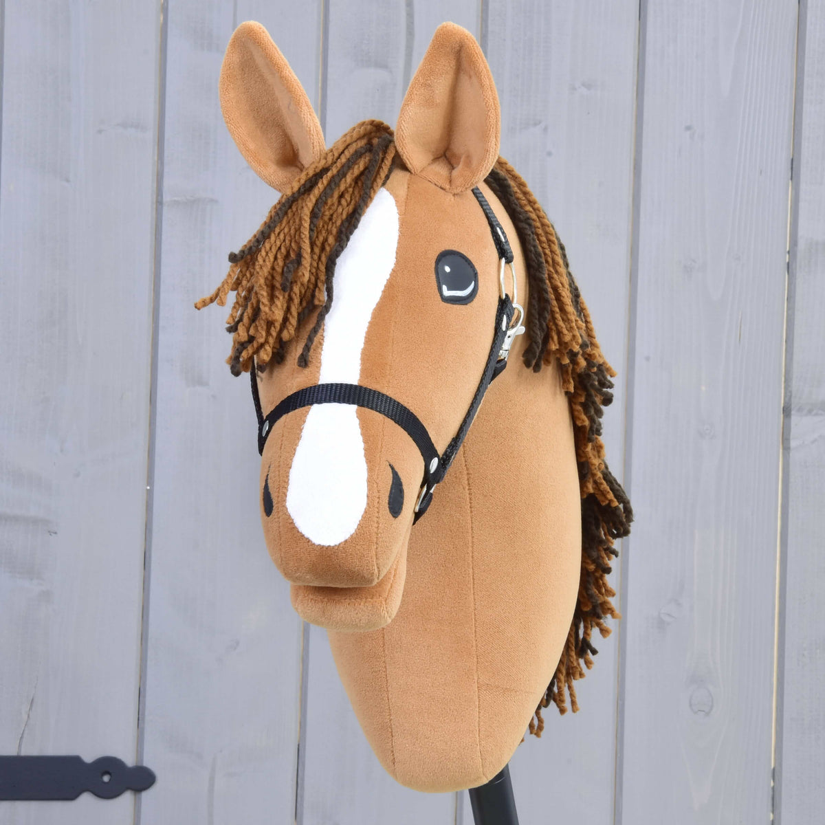 Front view of Hobby Horse Edward with a wide white blaze, brown yarn forelock and black halter