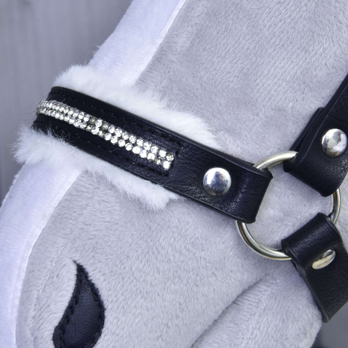 Close-up of the black noseband with two rows of rhinestones, white fur trim and a silver ring