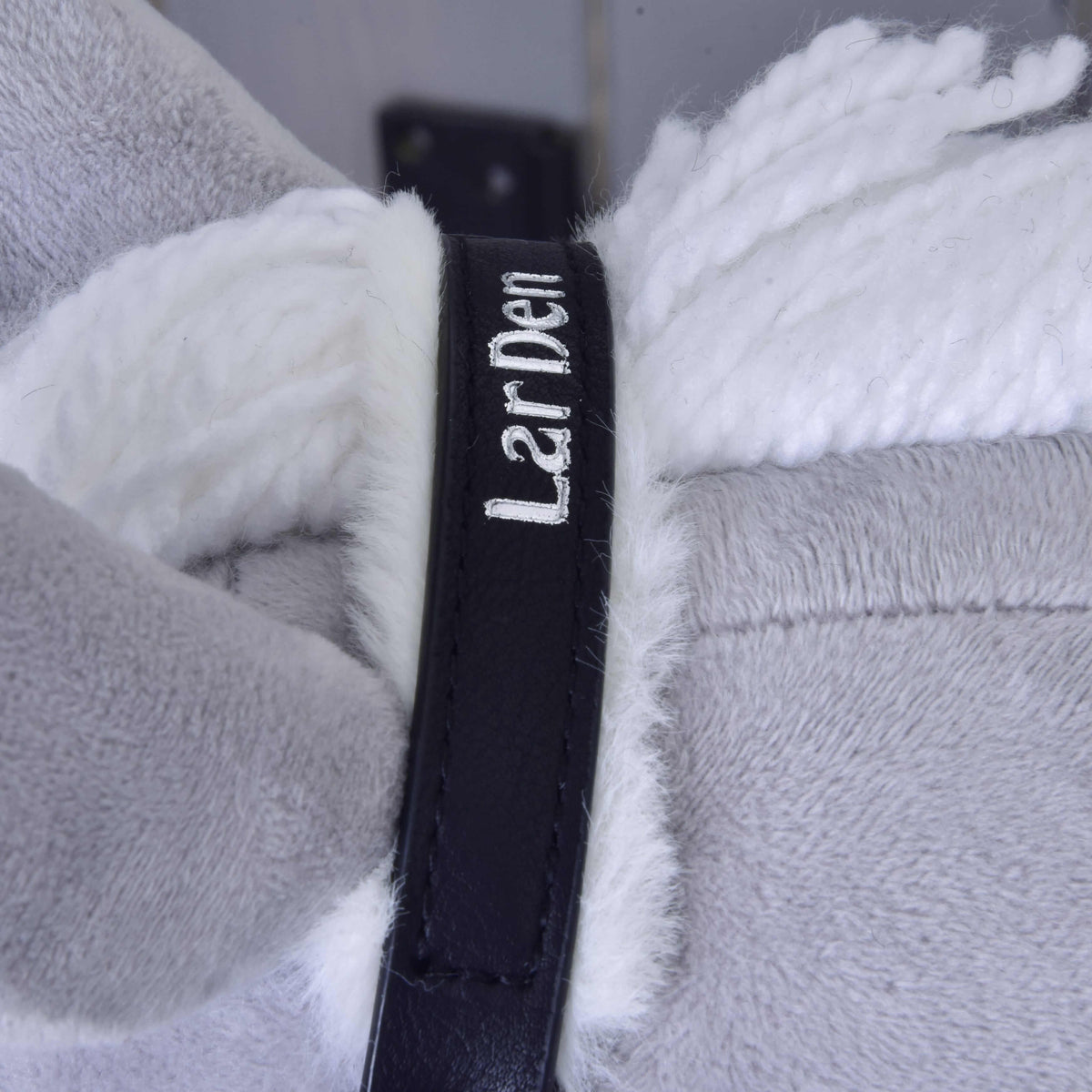 Close-up of the black crownpiece with white embroidered LarDen lettering and white fur lining by the yarn mane