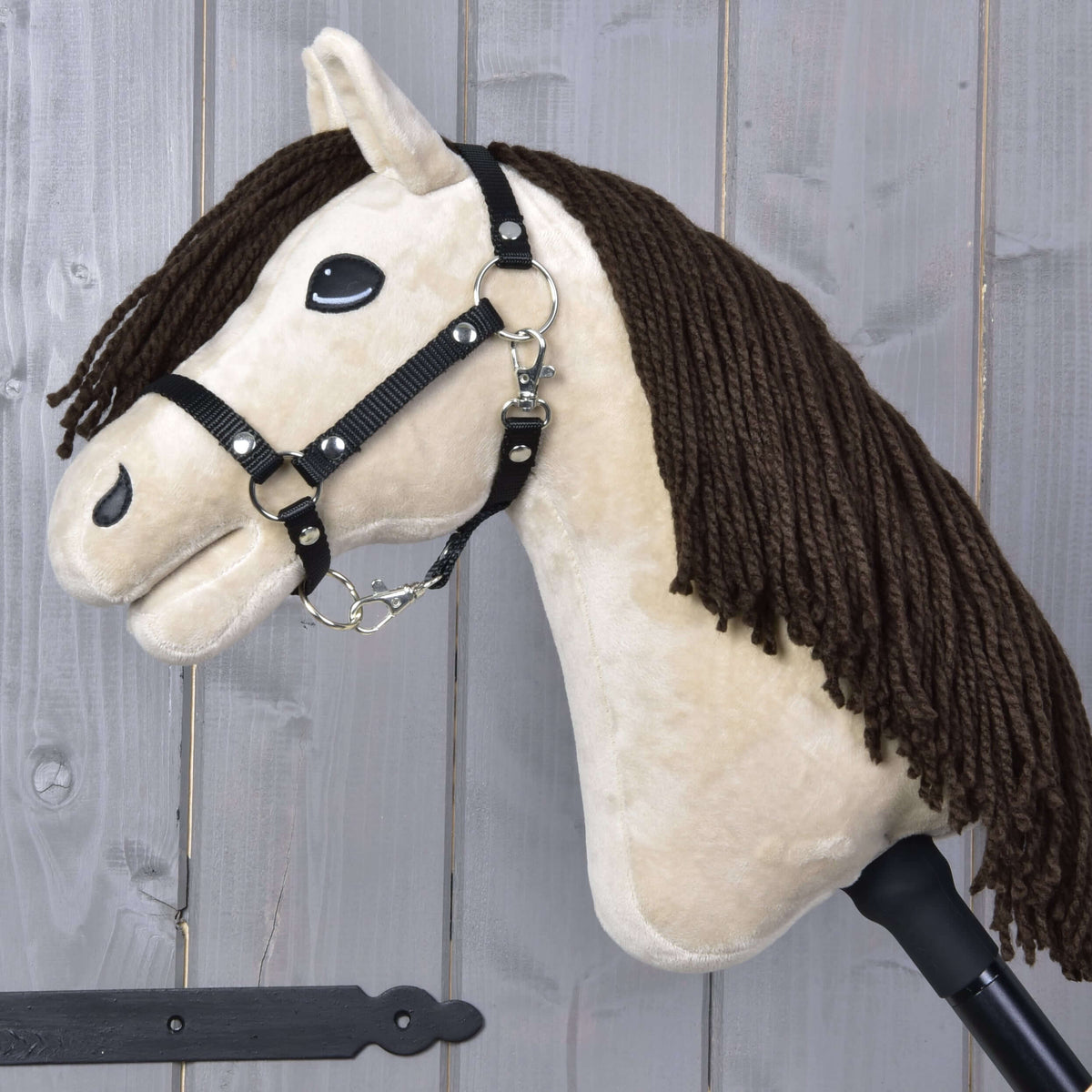 Hobby Horse Frederik LD avec licol noir de profil, crinière en fil brun foncé sur l’encolure crème et bâton noir