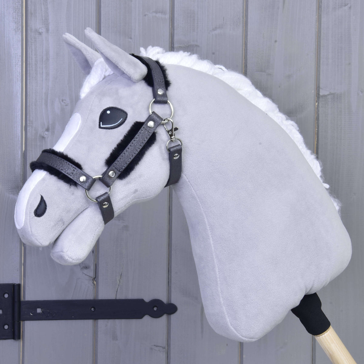 Lichtgrijze Hobby Horse met witte manen in het grafietgrijze glitterhalster met zwart bont op neusriem en bakstukken