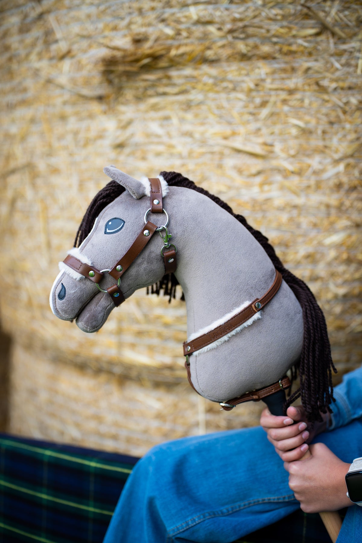 Close-up van Hobby Horse Guccini in bruine halster en borsttuig met fleecerand voor een strobaal