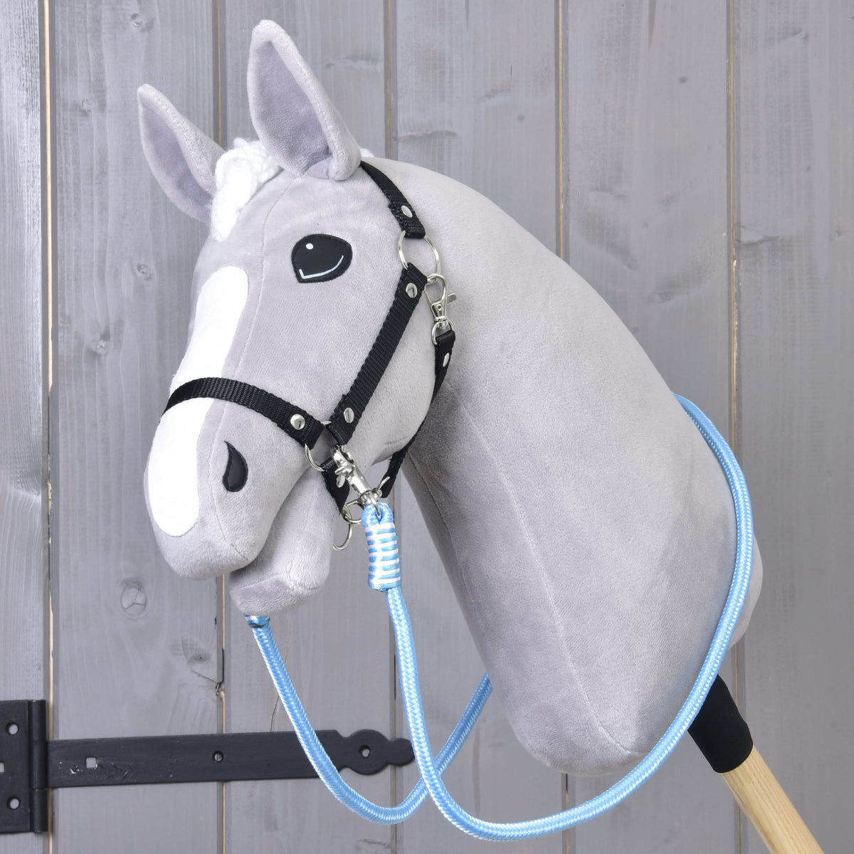 Lichtgrijze Hobby Horse met zwart halster en lichtblauwe Teugels Heaven onder de kin vastgemaakt