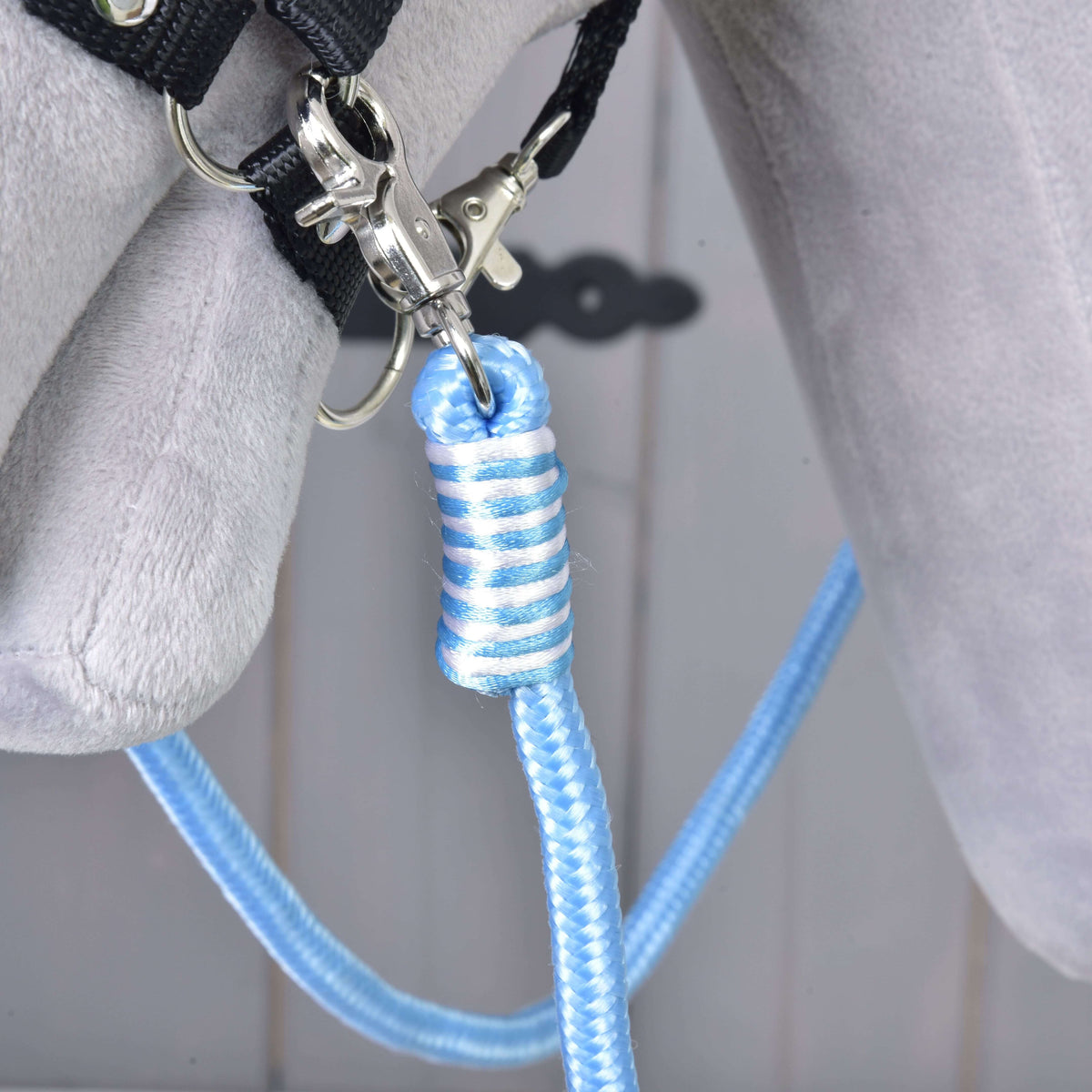 Close-up van de blauw-witte omwikkeling en zilveren karabijnhaak van de Teugels Heaven voor Hobby Horse aan het zwarte halster