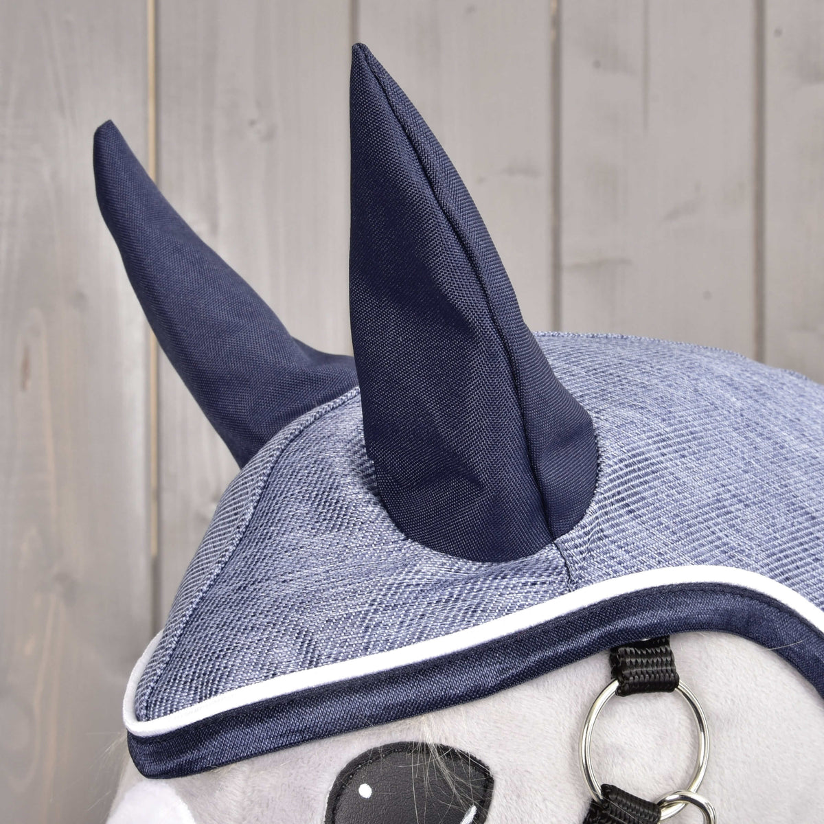 Gros plan sur la capuche de l’imperméable Jeans, oreilles bleu marine et dessus bleu denim bordé de marine et de blanc