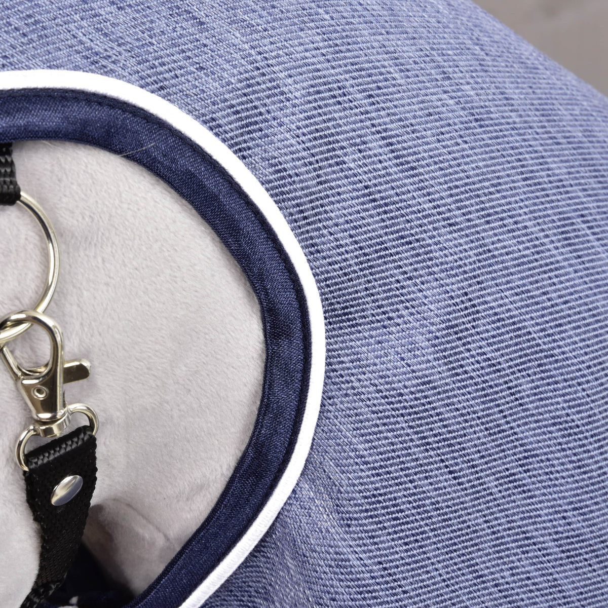 Gros plan sur l’imperméable Jeans : tissu bleu texture denim, bordure marine et passepoil blanc à l’encolure