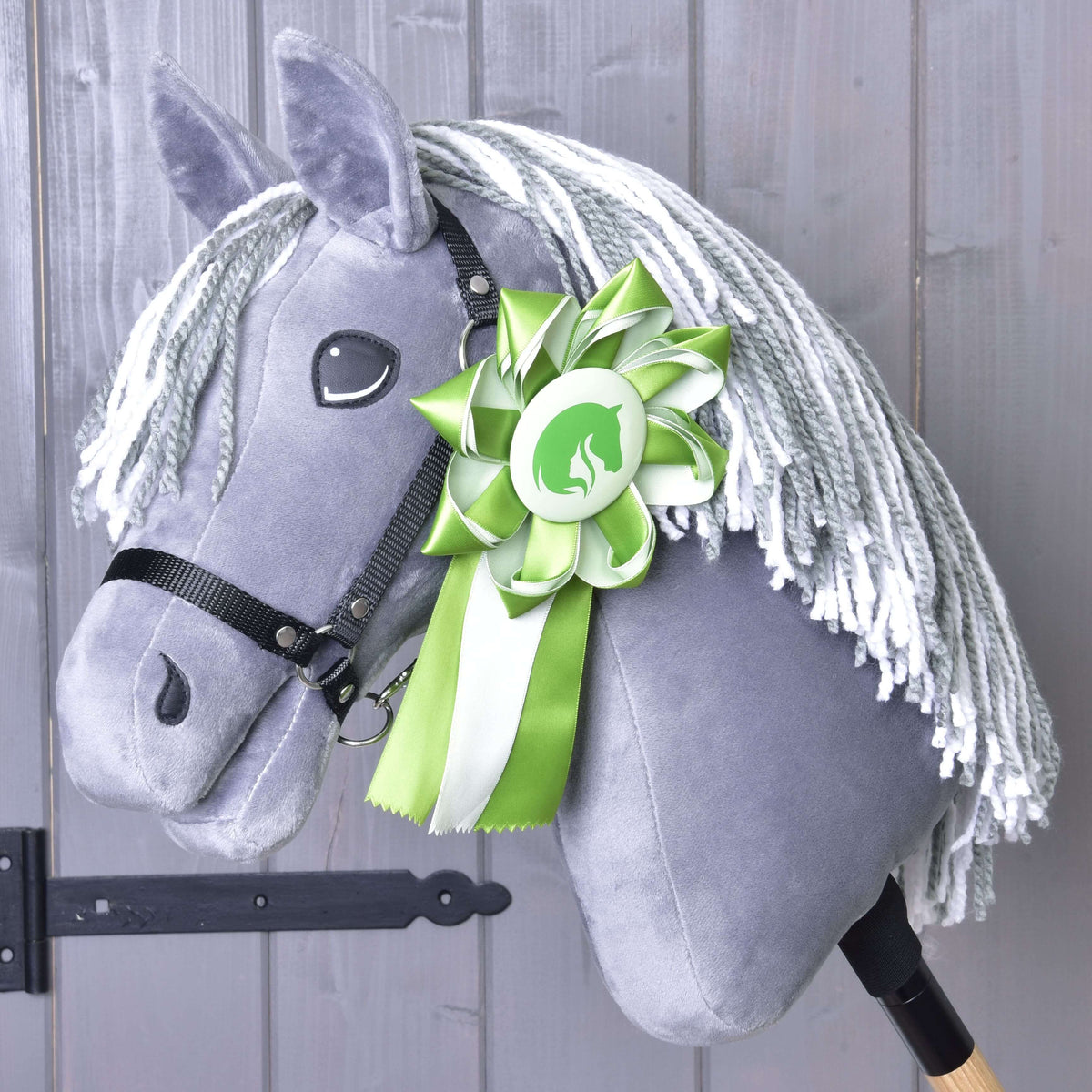 Hobby Horse gris en peluche à crinière en fil gris et blanc et licol noir, avec la cocarde verte épinglée à l’encolure