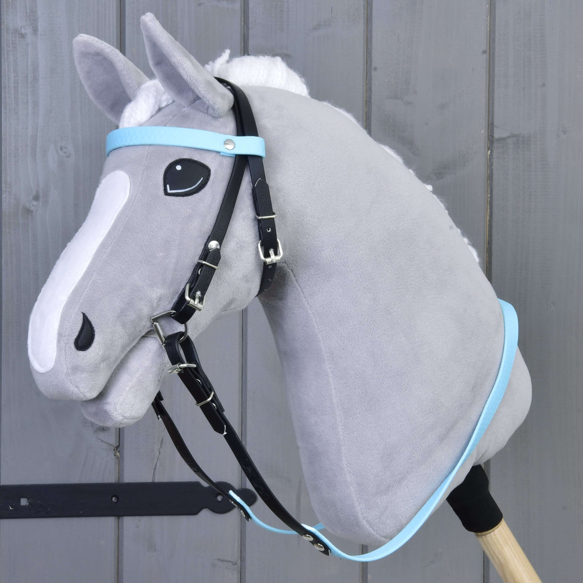 Bride complète sans muserolle Light Blue LarDen sur un Hobby Horse gris, montants noirs avec frontal et rênes bleu clair