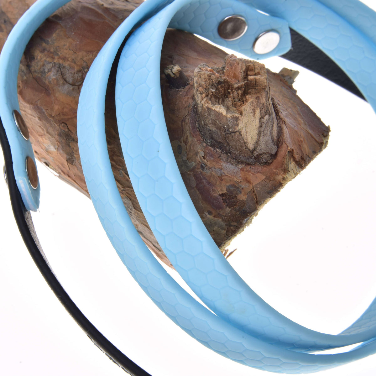 Close-up van lichtblauwe gerubberde teugels voor Hobby Horse met honingraatstructuur en zilveren klinknagels, om een tak gewikkeld