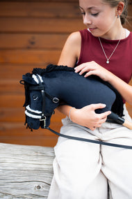 Fille en haut bordeaux tenant dans ses bras le Hobby Horse Mahal avec licol noir, ici avec une bride noire à fourrure blanche