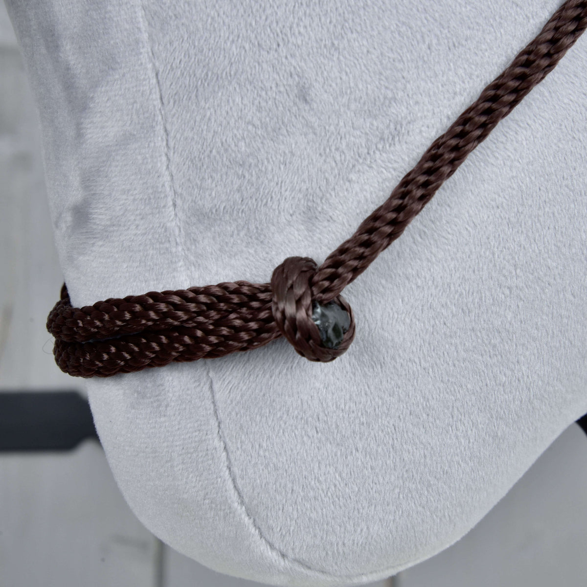 Close-up van de Cordeo Chocolate op lichtgrijs pluche: donkerbruin gevlochten touw door een knoop gehaald