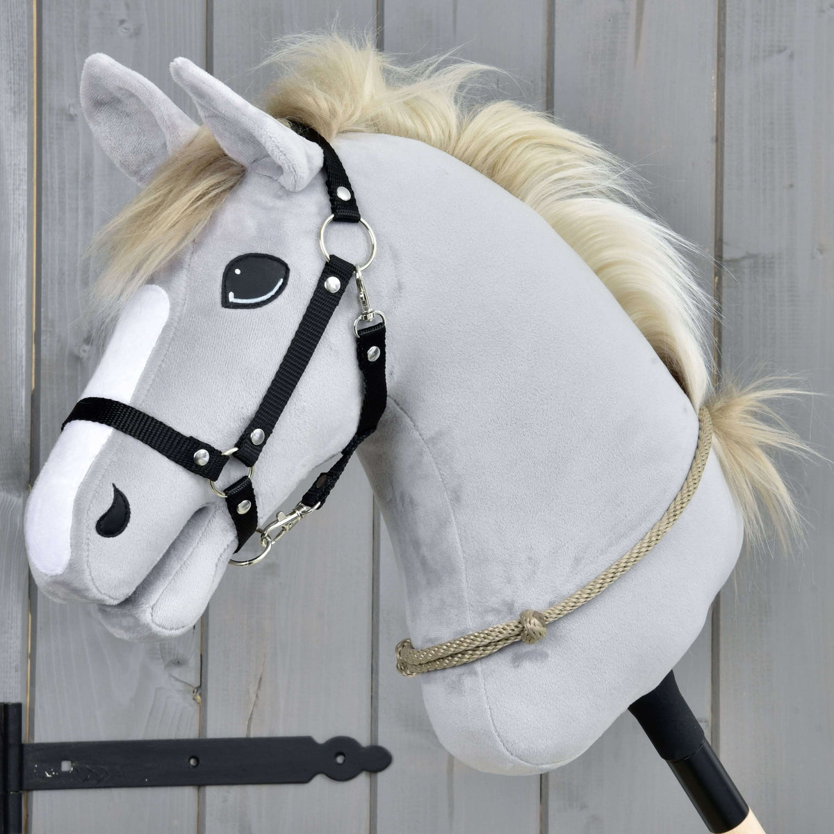 Hobby Horse gris clair avec licol noir portant le cordéo Eleganza, une corde beige grisé à nœud, bas sur l’encolure