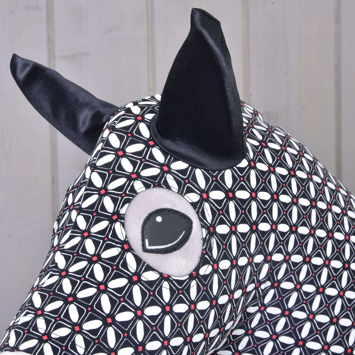 Close-up van het Hobby Horse beschermpak DeLuxe: zwart satijnen oor en ooguitsparing in het geometrische patroon