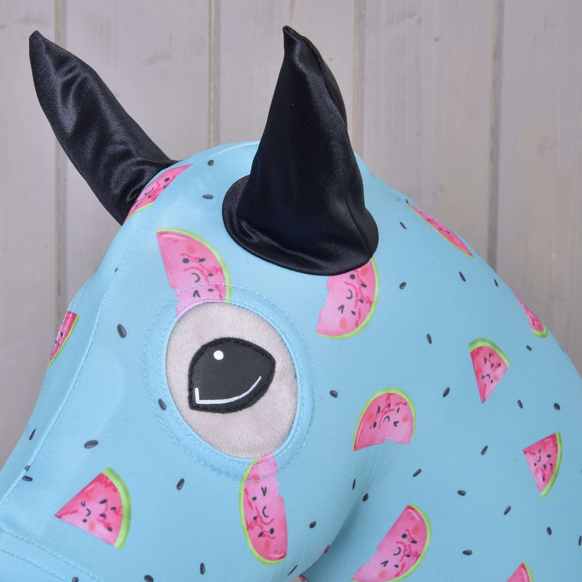 Close-up van het Hobby Horse beschermpak Melon: zwart satijnen oor en ooguitsparing in de watermeloenprint