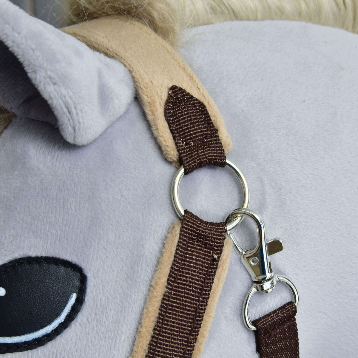 Close-up van zilveren ring en karabijnhaak onder het oor, waar de donkerbruine band het beige fleece kopstuk raakt