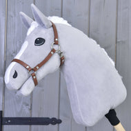 Grijze pluche Hobby Horse met witte manen en bles, met de halster van bruin kunstleer voor een grijze houten wand