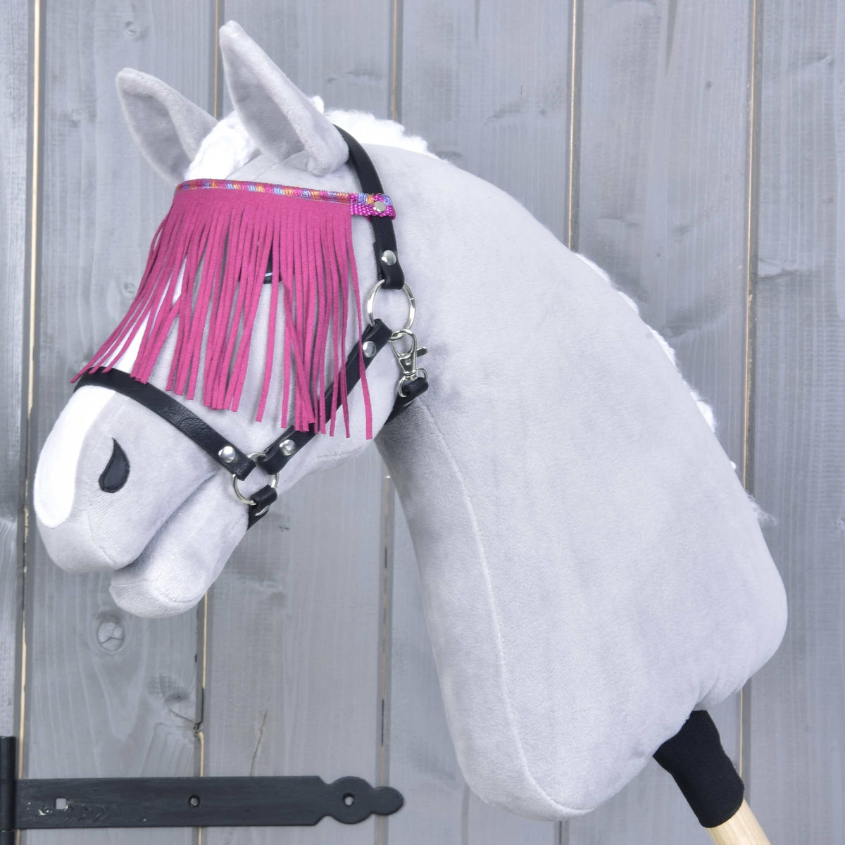 Grey Hobby Horse wearing the black halter, the pink fringe falling over its eyes from a glittery multicoloured band
