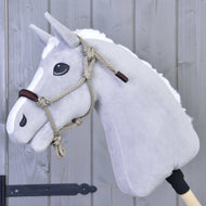 Grijze pluche Hobby Horse met witte manen en de beige touwhalster met bruine neusriem voor een grijze houten wand