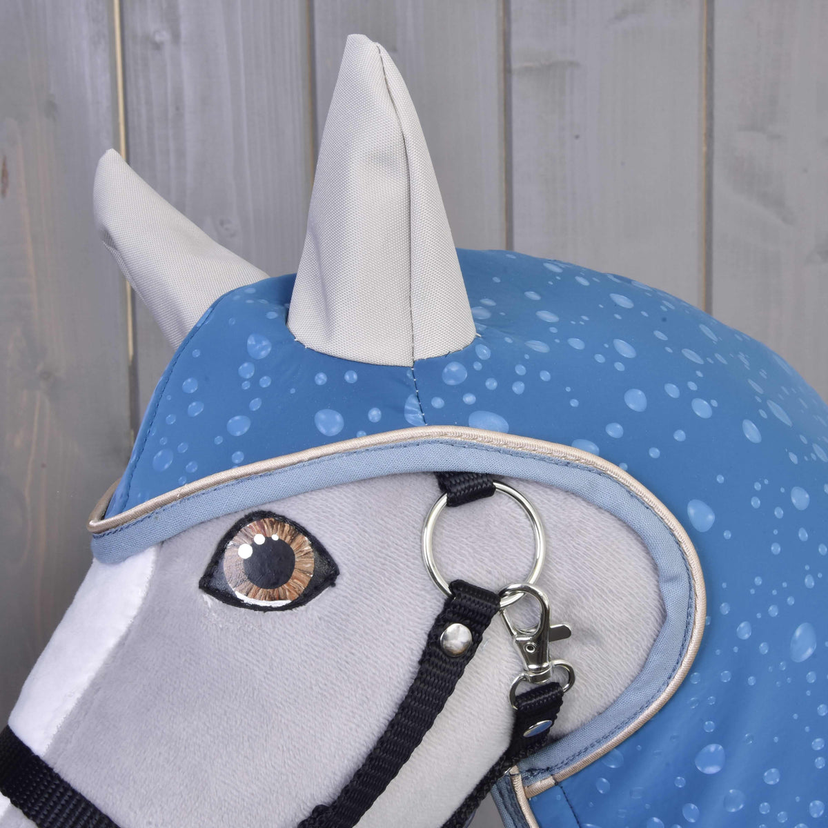 Close-up van de kap van regenjas Dolly met grijze oren en druppelprint boven het oog van een grijze Hobby Horse