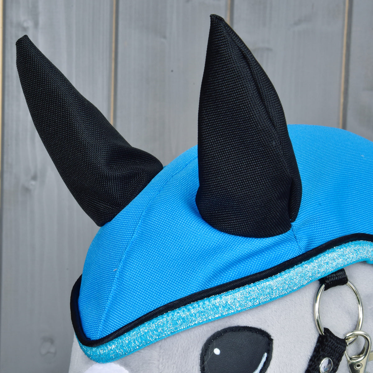Close-up of the black fabric ears on the sky blue hood with glittery trim and black piping above the eye