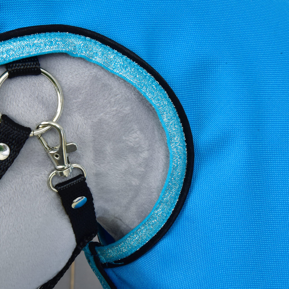 Close-up of the glittery light blue binding around the face opening next to the halter ring and snap hook