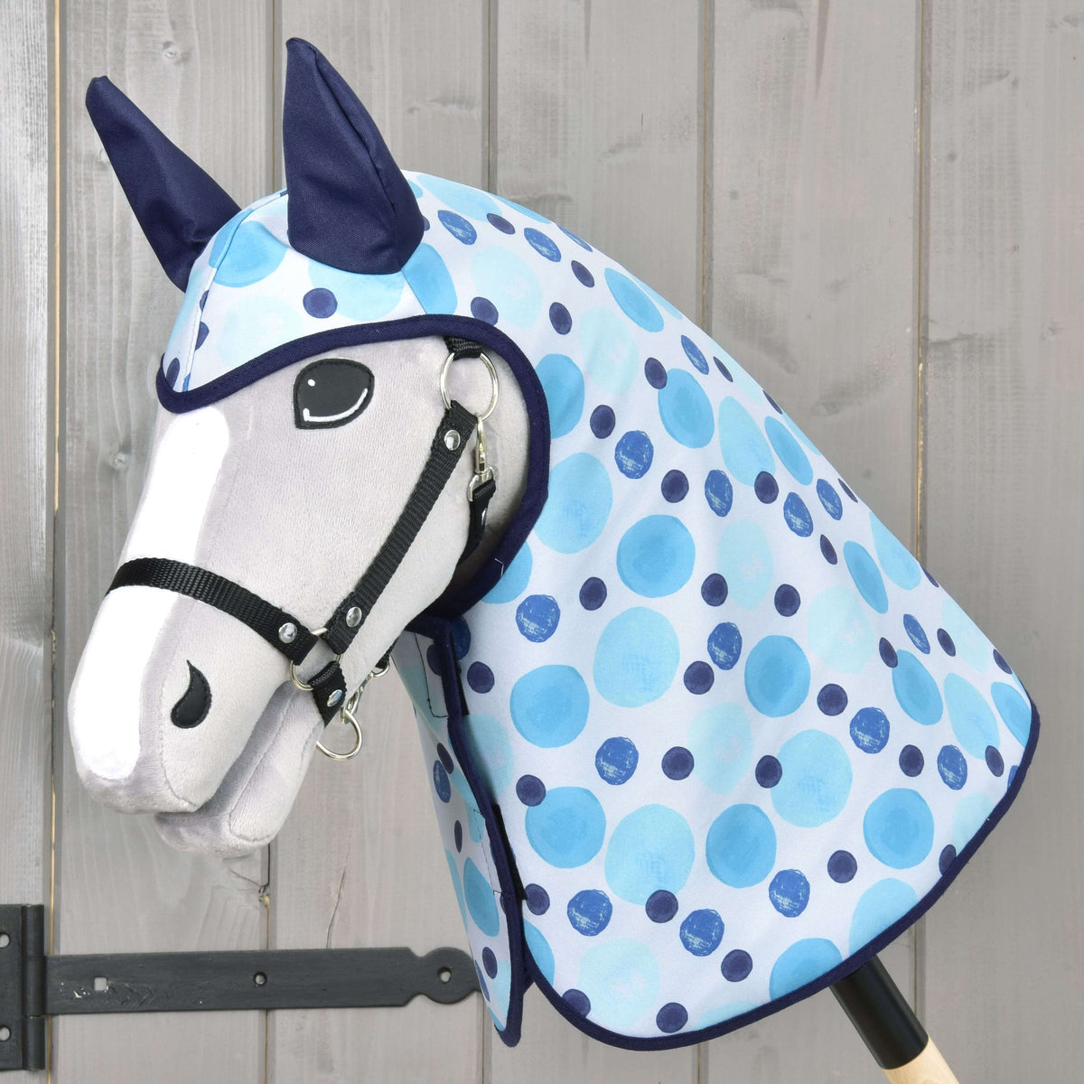 Lichtgrijze Hobby Horse met zwart halster in de Regenjas Bubbles met licht- en donkerblauwe stippen, donkerblauwe oren en rand