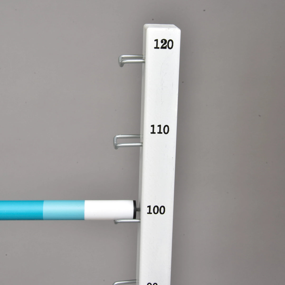 Turquoise-witte balk op de metalen haak bij 100 cm aan een witte standaard met markeringen tot 120