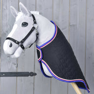 Grijze Hobby Horse met zwart halster in de zwarte gewatteerde reisdeken met blauw-rood-witte rand, schuin van voren