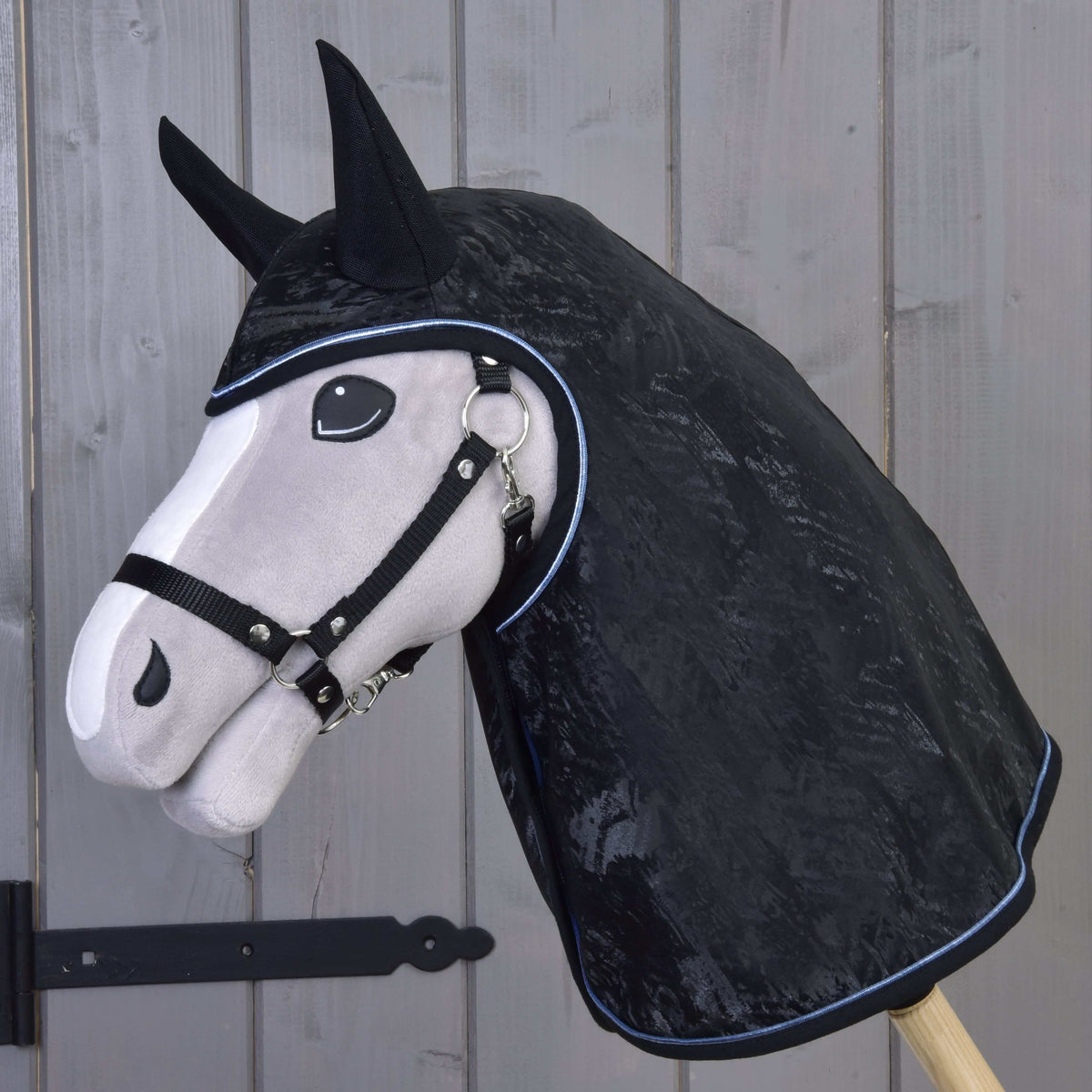 Hobby Horse gris avec licol noir portant l’imperméable noir marbré à oreilles noires et passepoil bleu clair