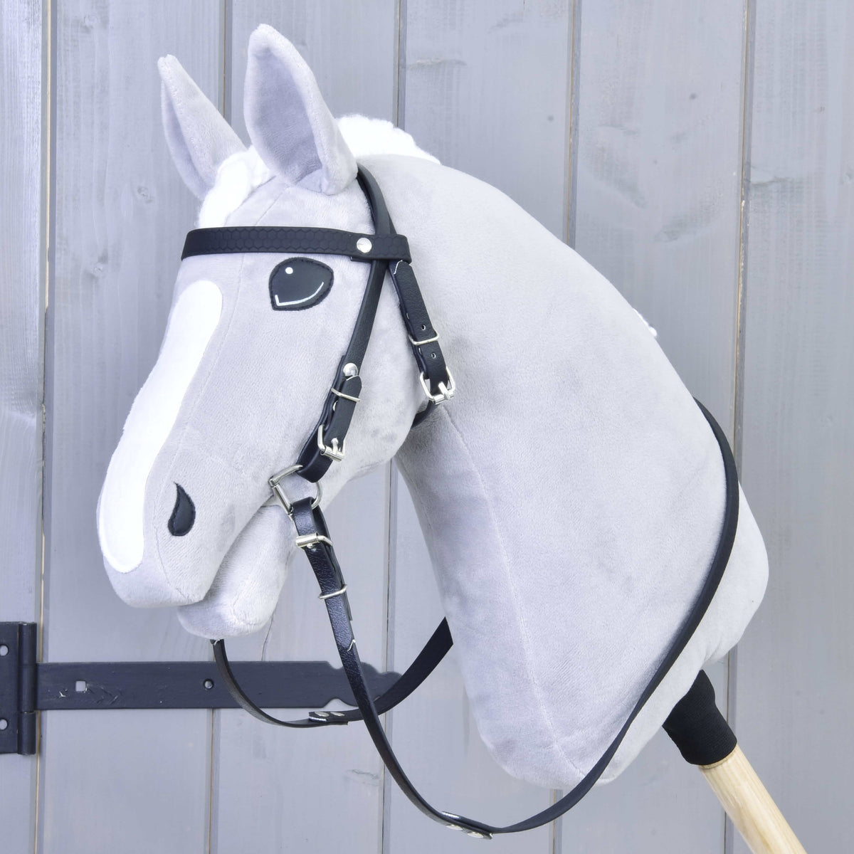 Hobby Horse gris à liste blanche portant la bride noire avec frontal, mors et rênes, mais sans muserolle