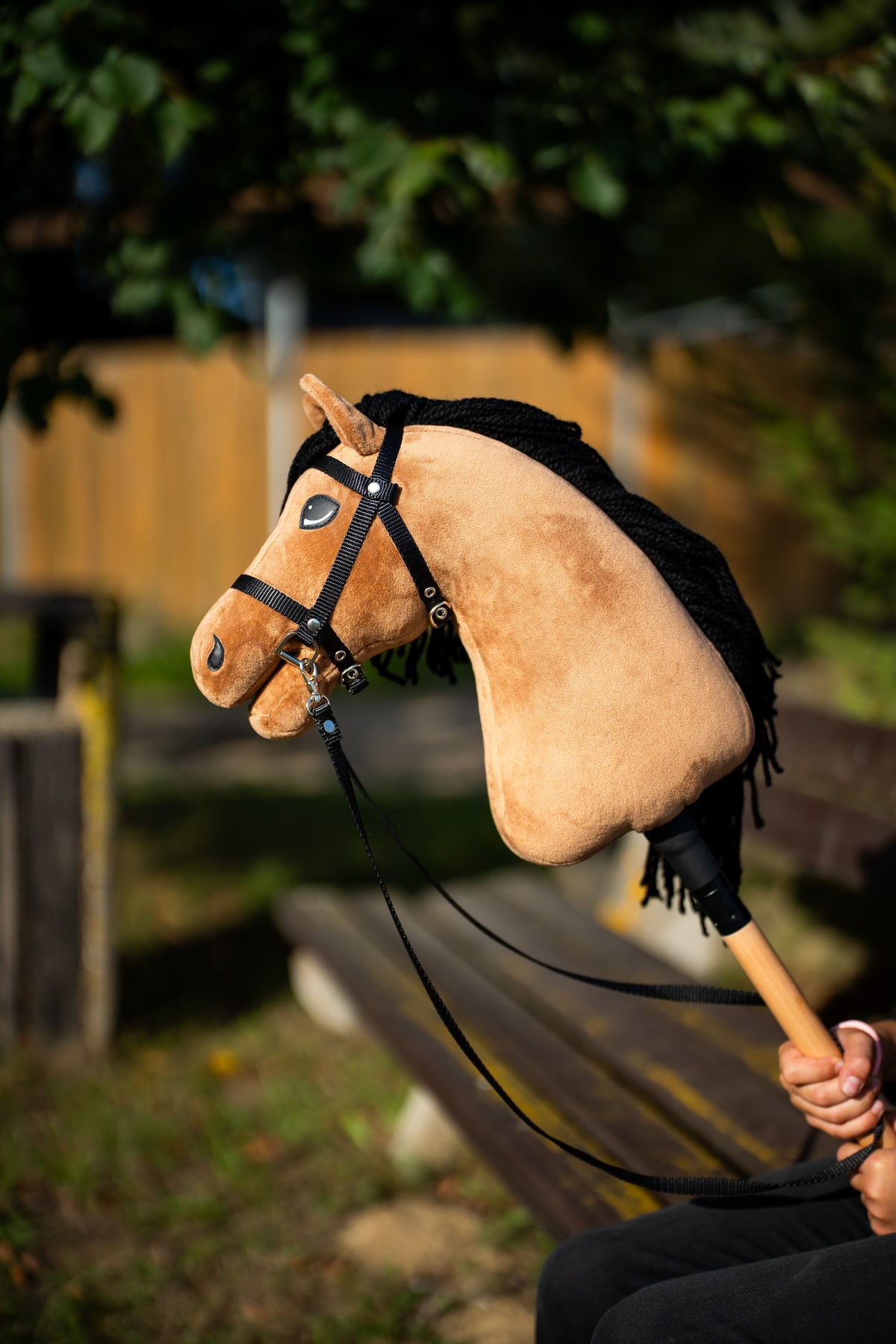 Hobby Horse Samantha met zandkleurig pluche en zwarte manen van garen in warm avondlicht, met zwart hoofdstel
