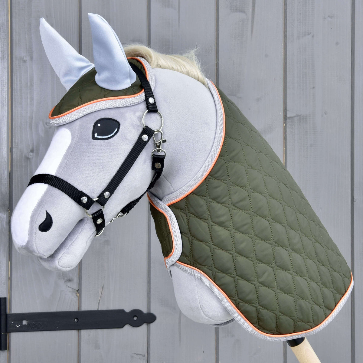 Light grey Hobby Horse in a black halter wearing the Set Moos, an olive green quilted blanket and matching ear bonnet