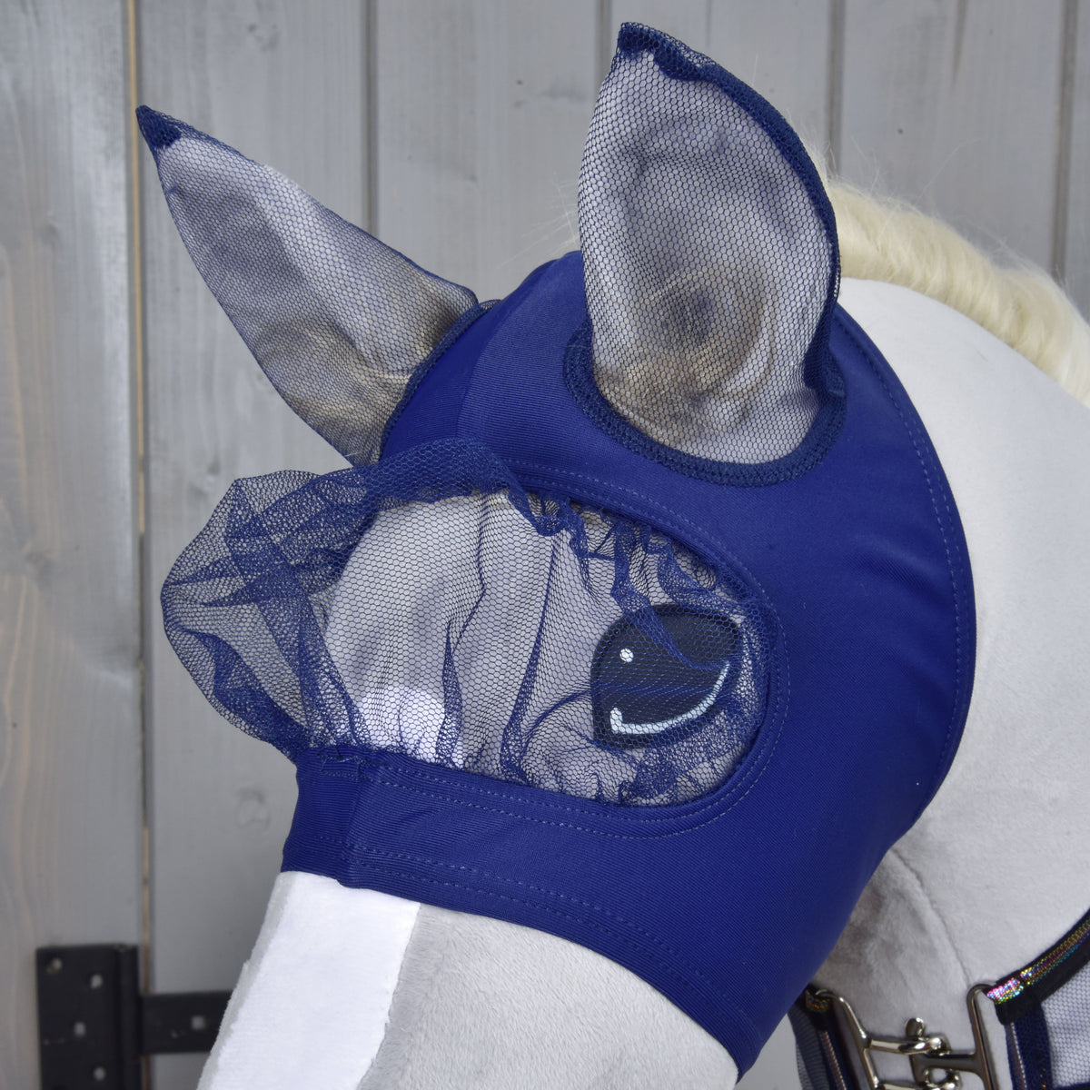 Close-up van het vliegenmasker uit de Set Fly Combo op een grijze Hobby Horse: donkerblauwe stof met gazen oren en geplooid ooggaas
